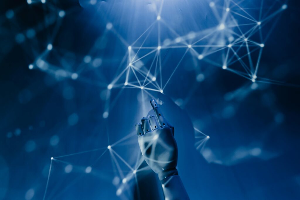 zipwp-image-8386440 A robotic hand reaching into a digital network on a blue background, symbolizing AI technology.